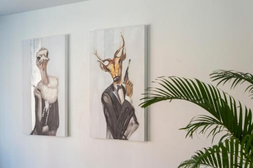 two framed pictures of a deer and a antelope on a wall at Suites Mana - Le Manaloft, Chic et moderne avec salle privée de Fitness en plein centre-ville de Rethel in Rethel