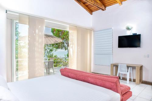 1 dormitorio con 1 cama, TV y mesa en Santorini Villas del Mar Santa Marta, en Santa Marta