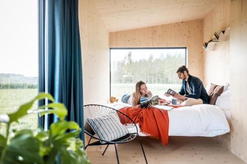 un hombre y una mujer sentados en una cama en una habitación en Slow Cabin - Sint-Truiden, en Sint-Truiden