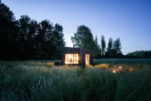 a small wooden house in a field of grass at Slow Cabin - Sint-Truiden in Sint-Truiden