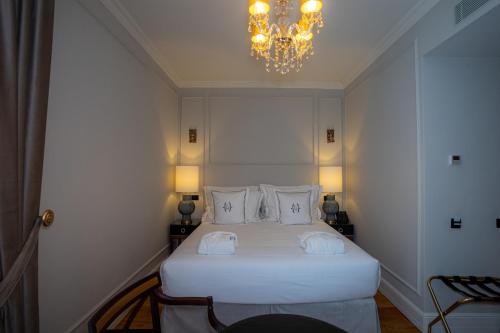 a bedroom with a large white bed with a chandelier at Solar do Requeijo by Luna Hotels & Resorts in Arcos de Valdevez