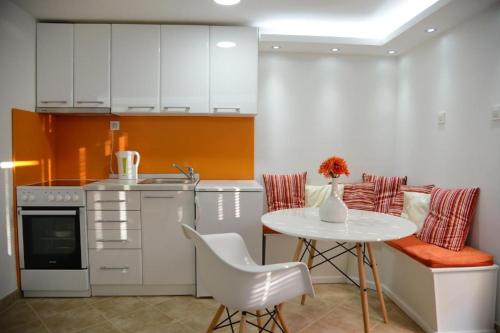 cocina con mesa blanca, mesa y sillas en Stylish basement with sea-view patio, en Dobrota