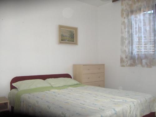 a bedroom with a bed and a dresser and a window at House for rent in Žrnovo