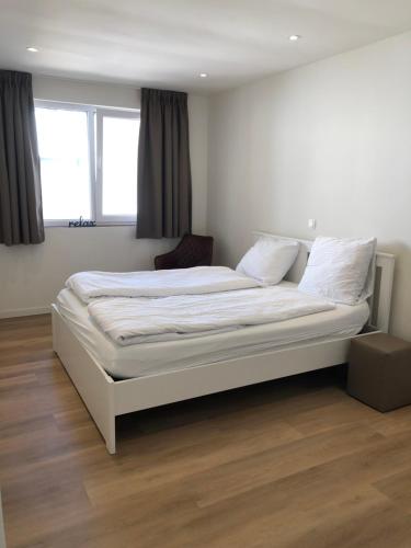Cama blanca en habitación con ventana en vakantie appartementen de Westpoort, en Aardenburg