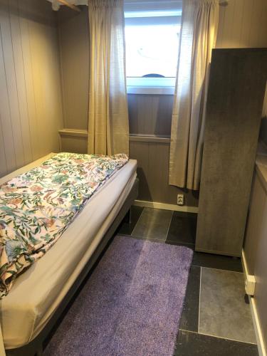 a small bedroom with a bed and a window at Basement Apartment Varadero in Lyngdal