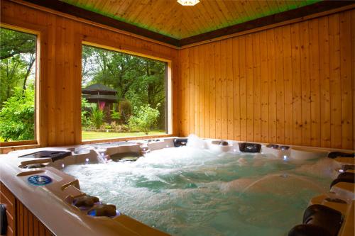 une baignoire jacuzzi dans une chambre avec une grande fenêtre dans l'établissement Stunning 4 bedroom country house - Hot Tub & Sauna, à Glasgow