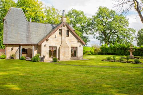 an old stone house with a grass yard at Stunning 4-Bedroom Country House with Hot Tub & Sauna near Loch Lomond in Glasgow