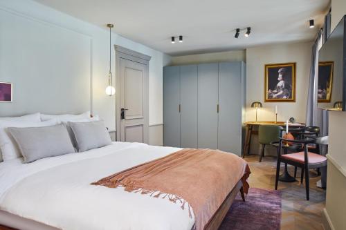 a bedroom with a large white bed and a desk at Martis Forum Heritage Hotel & Residence in Poreč