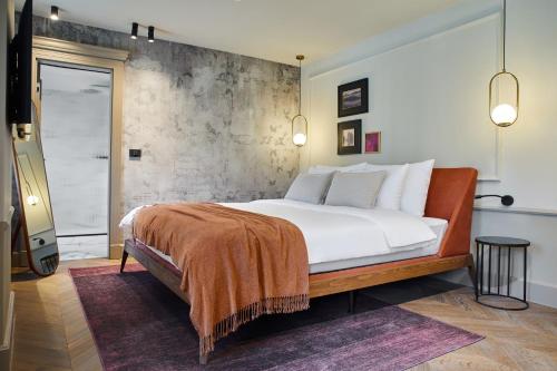 a bedroom with a large white bed with a concrete wall at Martis Forum Heritage Hotel & Residence in Poreč