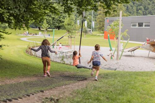 three girls playing on a swing in a park at lintharena ag in Näfels