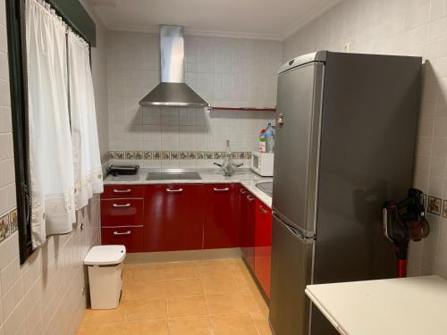 een keuken met rode kasten en een roestvrijstalen koelkast bij Apartamentos Illa Nova in Foz