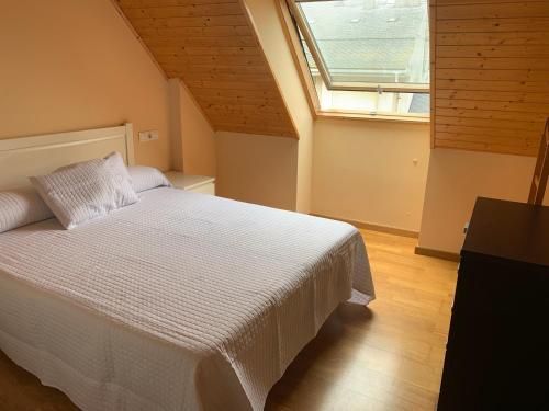 een slaapkamer met een wit bed en een raam bij Apartamentos Illa Nova in Foz