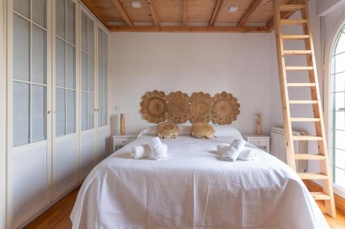 a bedroom with a bed with white sheets and a ladder at Fidalsa Majestic in Puente Arce