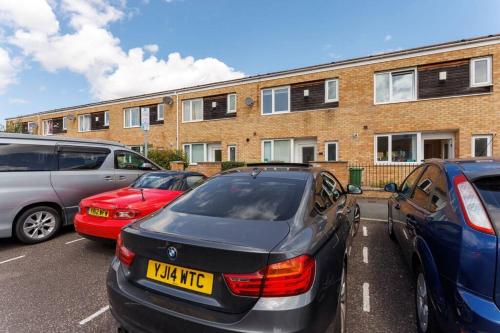 a parking lot with cars parked in front of a brick building at Sunshine Terrace by Happy Sunshine Stay in Manchester