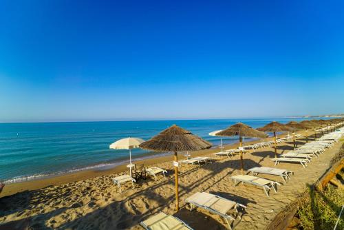 eine Reihe von Sonnenschirmen und Stühlen am Strand in der Unterkunft Sikania Resort & Spa in Licata