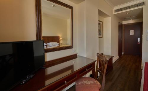 a room with a television and a mirror at Volos Palace in Volos