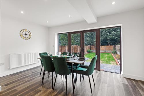 a dining room with a table and green chairs at Walsall - 4 Bedroom House, Wi-Fi, Garden , Sleeps 8 - JRR Stays in Bescot