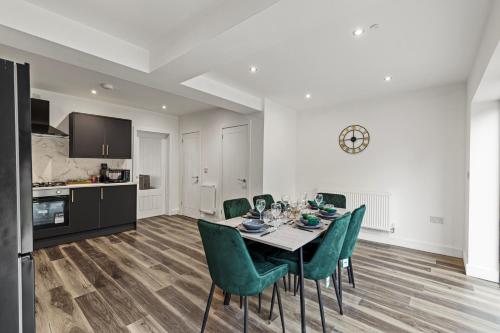 a dining room with a table and green chairs at Walsall - 4 Bedroom House, Wi-Fi, Garden , Sleeps 8 - JRR Stays in Bescot