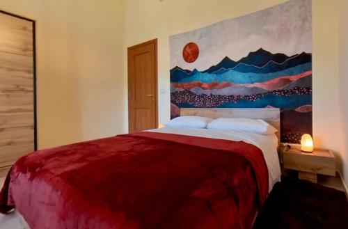 a bedroom with a red bed with a painting on the wall at LOVE NEST Abruzzo in Scoppito