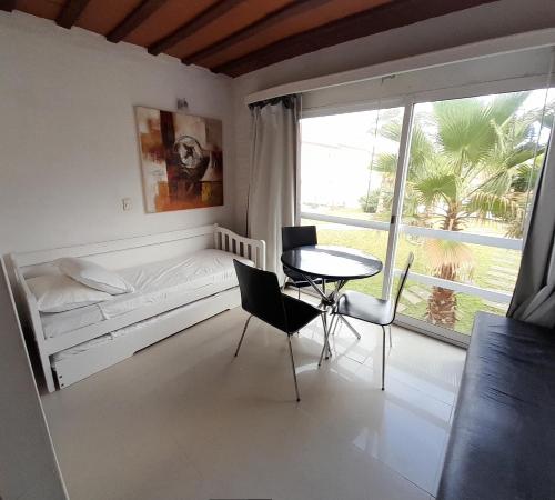 a room with a table and a bed and a table and chairs at Punta del Este Arenas Hotel in Punta del Este