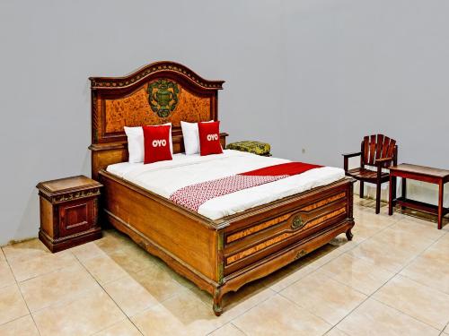 ein Schlafzimmer mit einem großen Holzbett mit roten Kissen in der Unterkunft OYO 3479 Hotel Intan in Banyumas