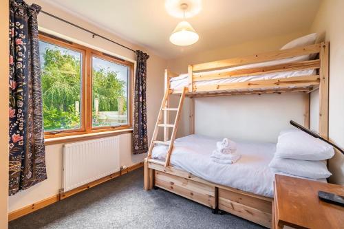 1 Schlafzimmer mit Etagenbetten, einem Schreibtisch und einem Fenster in der Unterkunft Langridge Highland Home in Badcaul