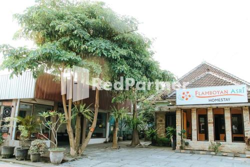 a store with trees in front of a building at Flamboyan Asri Syariah Mitra RedDoorz near Kampung Inggris Pare in Pare
