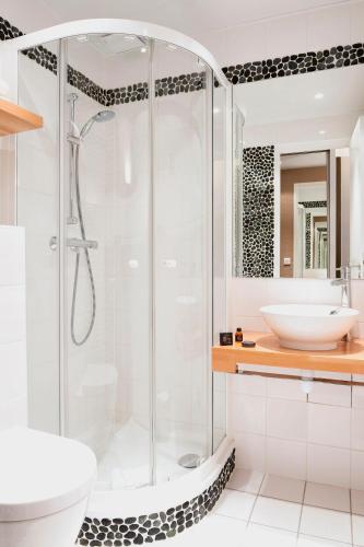 une salle de bain blanche avec une douche et un lavabo dans l'établissement Excelsior Opera, à Paris