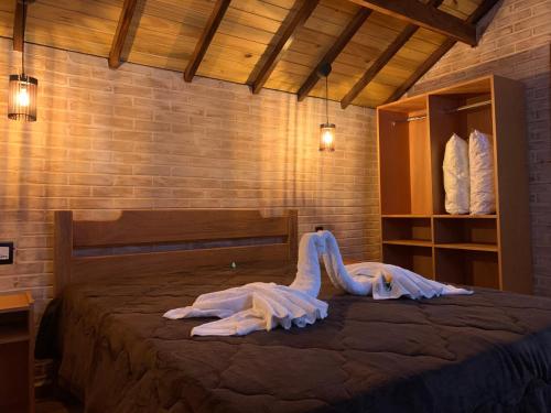 a bedroom with a bed with a dress on it at Chales Bela Serra in Monte Verde