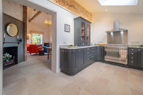 a kitchen with gray cabinets and a fireplace at Luxurious rural retreat - Holt Coach House in Sudbury