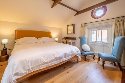a bedroom with a bed and two blue chairs at Luxurious rural retreat - Holt Coach House in Sudbury