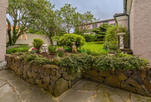 a stone retaining wall with a garden in front of a building at visitHOMES Faroe Islands in Leirvík