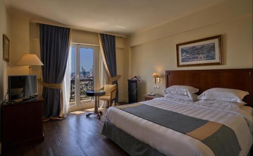 a hotel room with a large bed and a balcony at Volos Palace in Volos