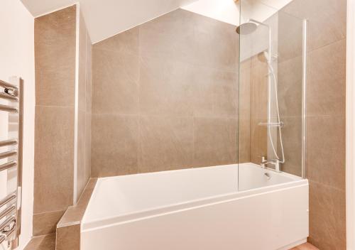 La salle de bains est pourvue d'une baignoire blanche et d'une douche. dans l'établissement The Cartlodge, à Woolpit