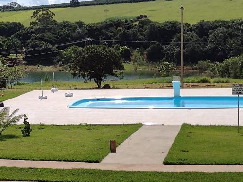 an empty swimming pool with a lake in the background at Pousada Epicurista in Capitólio