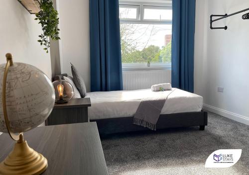 a bedroom with a bed with blue curtains and a window at Luke Stays - Pembroke Avenue in Walker Gate