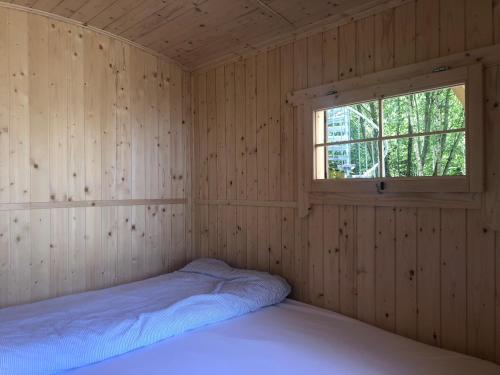 um quarto com uma cama num quarto de madeira com uma janela em Schäferwagen im Herzen vom Unterallgäu em Erkheim