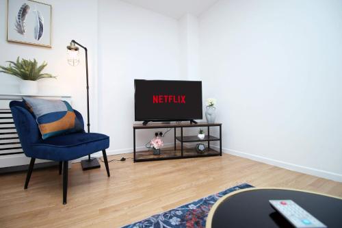 a living room with a tv and a blue chair at 2 Bedroom House on Holmes Hill Road- Free Parking, Wi-Fi & Patio in Bristol