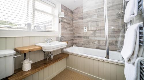 a bathroom with a sink and a bath tub at The Sherborne Cottage in Sherborne