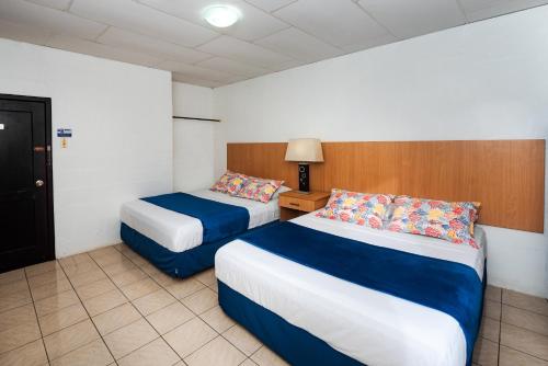 a hotel room with two beds and a lamp at Hostal North Seymour in Puerto Ayora