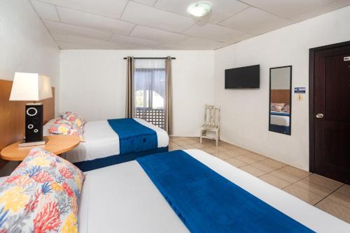 a hotel room with two beds and a television at Hostal North Seymour in Puerto Ayora