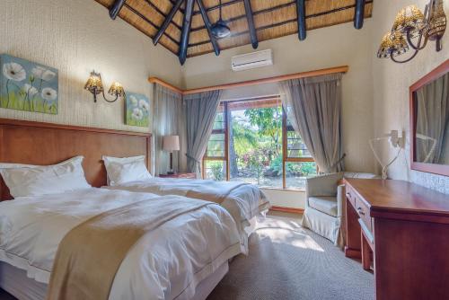 a bedroom with two beds and a desk and a window at Kruger Park Lodge Unit No. 547 in Hazyview