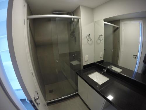 uma casa de banho com uma cabina de duche em vidro e um lavatório. em Loft 1303 Maxplaza, Encantador, piscina, garagem em Canoas