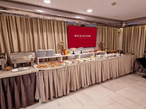 a buffet line with plates of food and a screen at Senator Hotel in Tirana