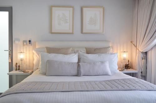1 cama blanca con almohadas blancas y 2 lámparas en Augusta Palms - White Room, en Centurion
