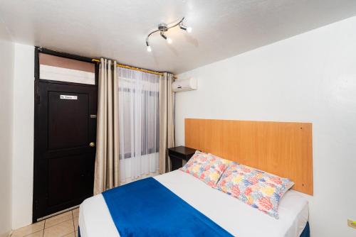 a bedroom with a bed and a black door at Hostal North Seymour in Puerto Ayora