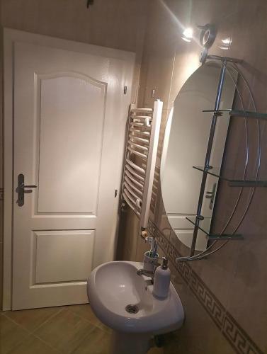 een badkamer met een witte wastafel en een spiegel bij W Apartman in Gornji Milanovac