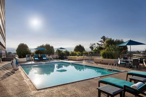a swimming pool with chairs and umbrellas on a hotel at Sonesta San Jose - Milpitas in Milpitas