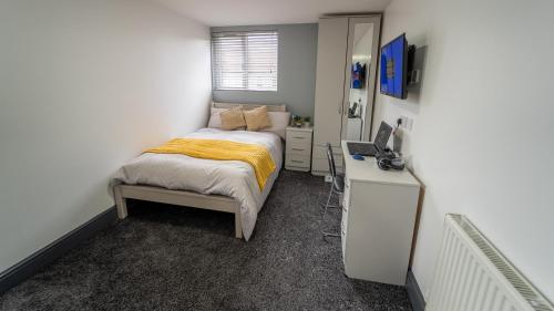 a bedroom with a bed and a desk with a computer at Spacious studio near city centre! in Birmingham