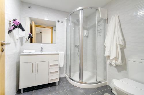 uma casa de banho branca com um chuveiro e um lavatório. em Duerming Family Viveiro 4 Rooms em Viveiro